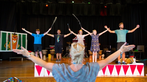 Males dancing on stage with teacher in foreground directing them