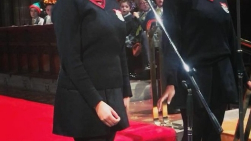 Two female students singing on stage into microphones