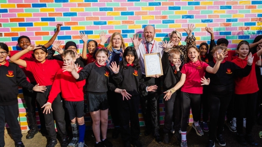 Students and teacher holding up certificate against a colourful wall