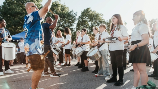 Adults and children playing drums outside