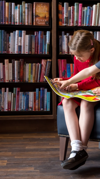 Two children reading a book in a library