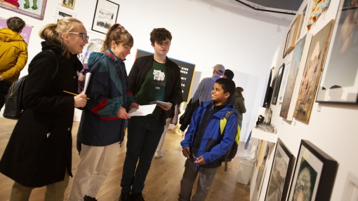 Four young people in a row, discussing art work on display on the wall in front of them