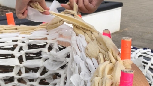 Two hands create a sculpture out of wooden sticks.