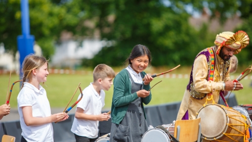 Pupils playing dhol drums, with a professional dhol drummer leading the procession.