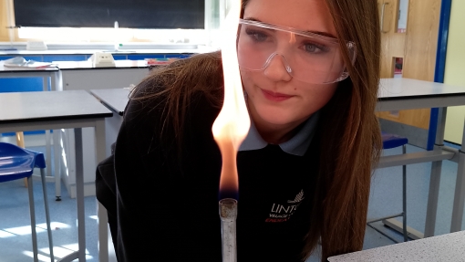A young girl is looking at the flame of a Bunsen burner