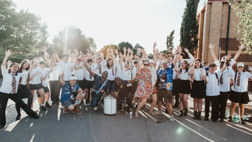 A group photo taken outside of students and staff all cheering.