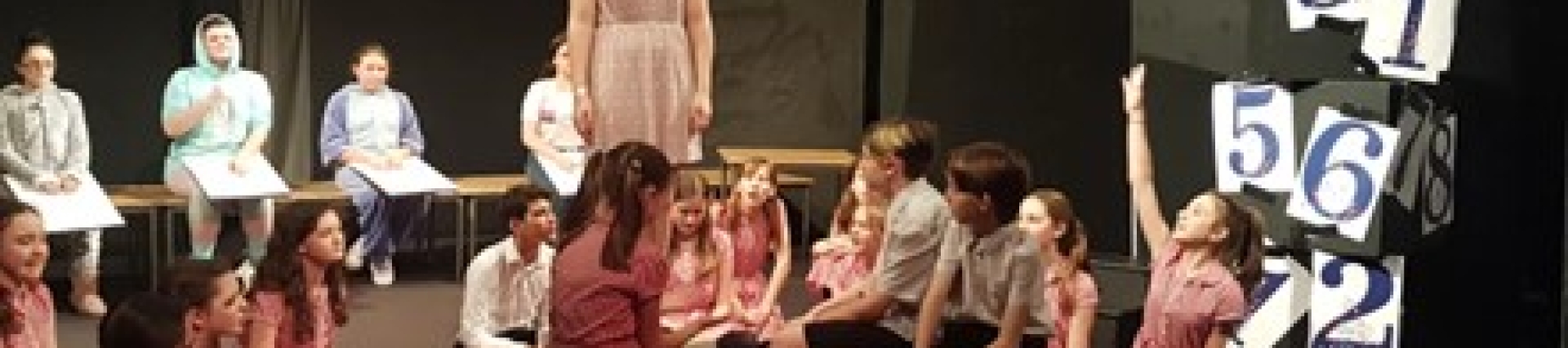 A group of young people stand on a stage acting