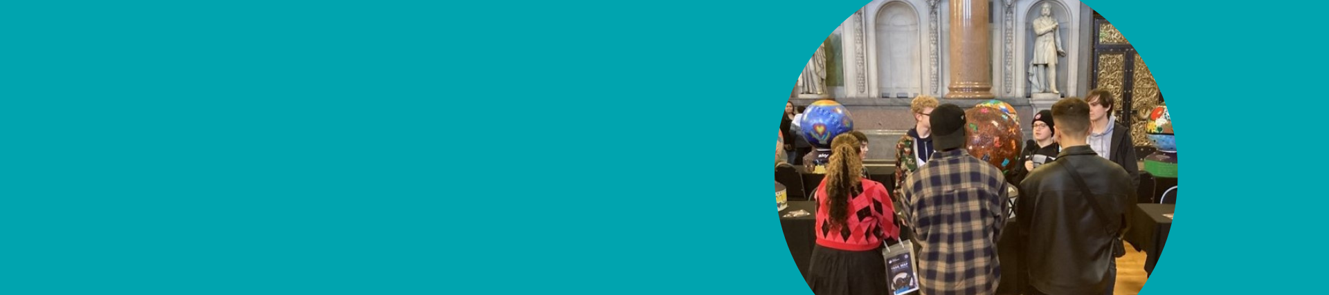 A teal banner with a photo of young people talking to visitors at an art exhibition, with their art work on display in the background.