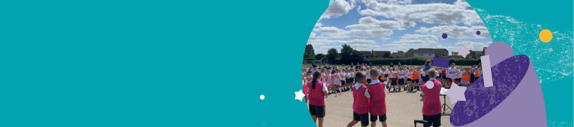 Large group of children gathered outdoors on a sunny day, standing in lines on a playground or sports area. Some wear bright pink bibs while others are in white and orange tops. A person at the front appears to be addressing the group, with houses and trees visible in the background under a partly cloudy sky.