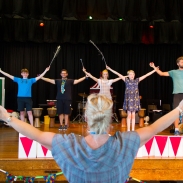 Males dancing on stage with teacher in foreground directing them
