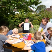 Group of students sitting outside at a table drawing with their teacher