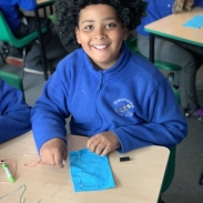 Pupil learning to sew and smiling proudly 