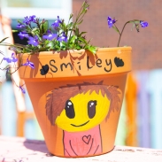 A terracotta plant pot with the words 'smiley' written on it and a drawing of a character smiling 