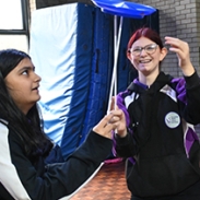 Two pupils concentrating, looking up as they balance a plate on sticks 