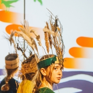 Young people perform on stage and they are wearing feathered headdresses.