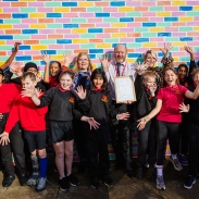 Students and teacher holding up certificate against a colourful wall