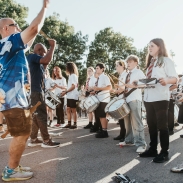 Adults and children playing drums outside